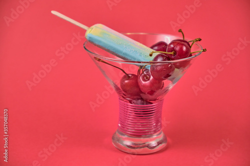 Multi-colored ice cream with ripe red cherries in a beautiful glass vase.Macro.