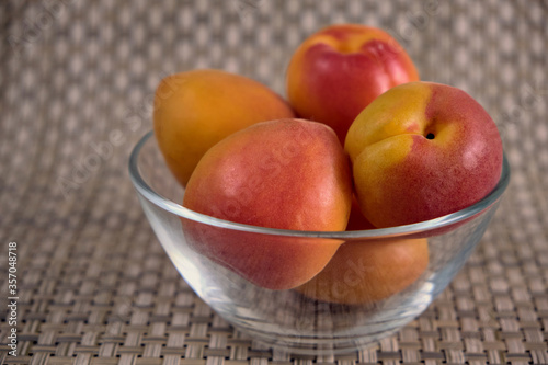 Fresh juicy apricots in a transparent glass plate. Macro.