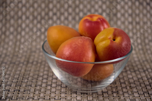 Fresh juicy apricots in a transparent glass plate. Macro.