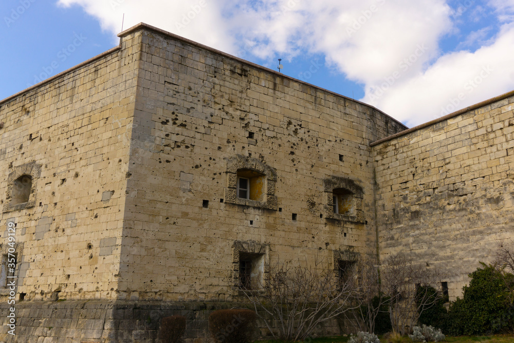 Wall of the ancient European castle with small windows and a lot of gunshots residues. Vintage fortified structure. Wall of the ancient European castle with small windows and a lot of gunshots residues. Vintage fortified structure.