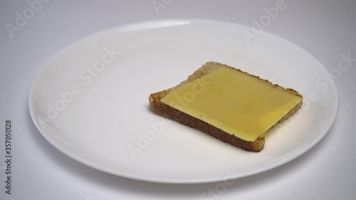 On dried toast lay cheese and avocado slices. Hands of a girl with red manicure