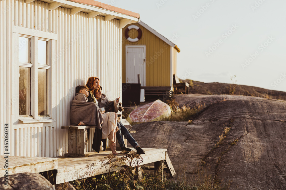 Son pointing to mother while sitting against cabin during sunny day Son pointing to mother while sitting against cabin during sunny day