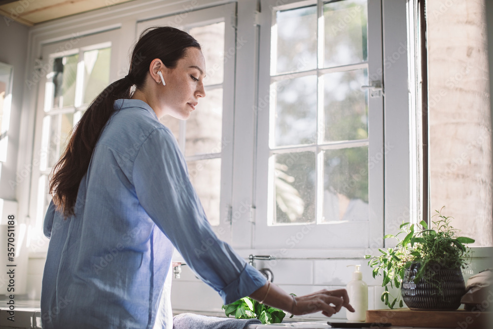 Side view of businesswoman using smart phone on kitchen counter at home office Side view of businesswoman using smart phone on kitchen counter at home office