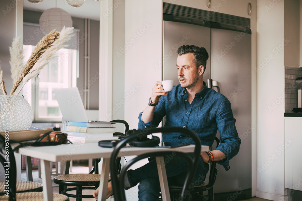 Man having a coffee in kitchen working at home Man having a coffee in kitchen working at home
