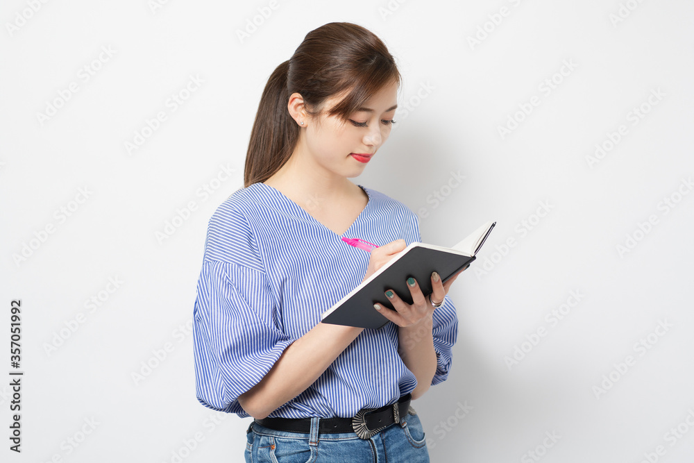 ノートにメモを書く若い女性 ノートにメモを書く若い女性