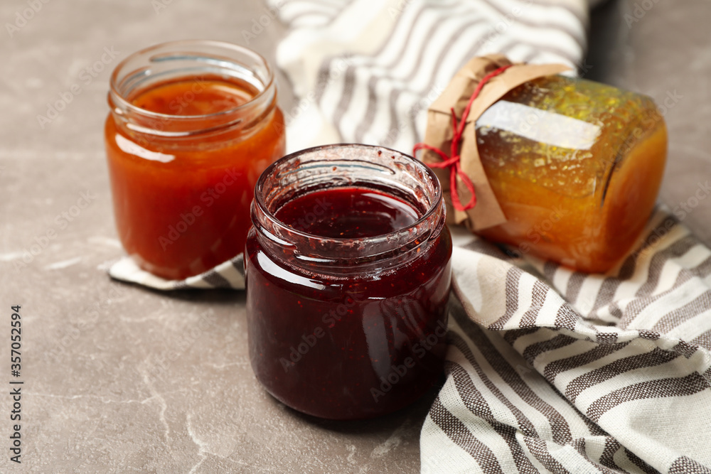 Napkin and glass jars with jam on gray background, close up Napkin and glass jars with jam on gray background, close up