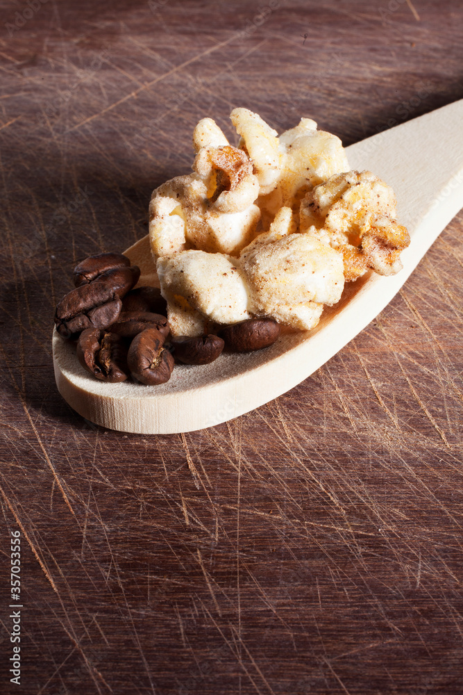 Gourmet cinnamon and coffee popcorn on wooden spoon over a wood cutting board background.