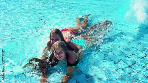Children having fun in beach resort aqua park with wave . Kids sisters hug each other lying in wave shallow water in swimming pool.
