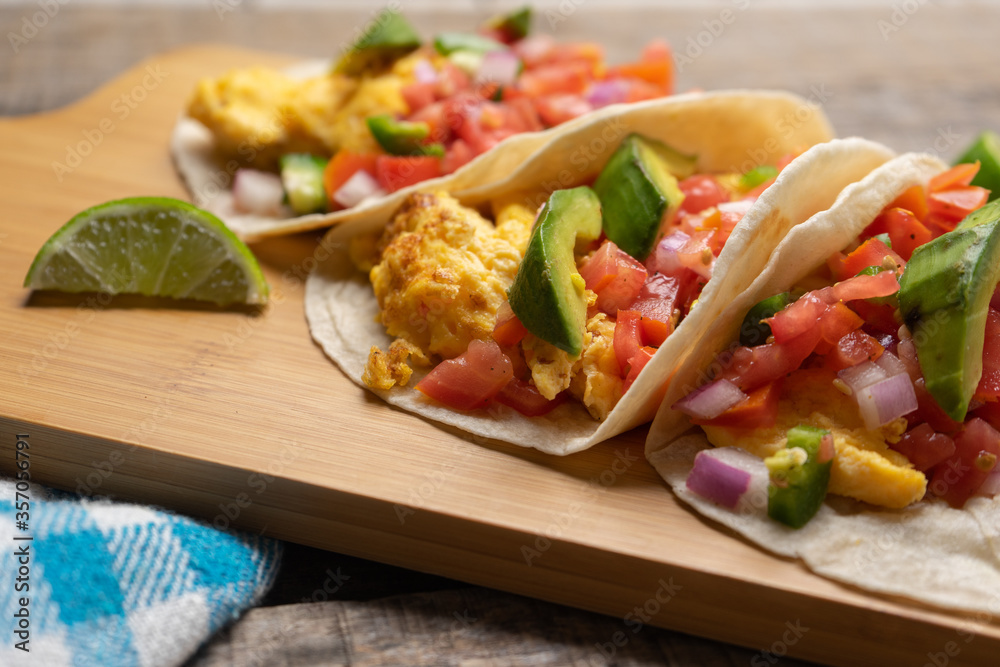 Breakfast egg tacos with flour tortilla and fresh sauce on wooden background Breakfast egg tacos with flour tortilla and fresh sauce on wooden background