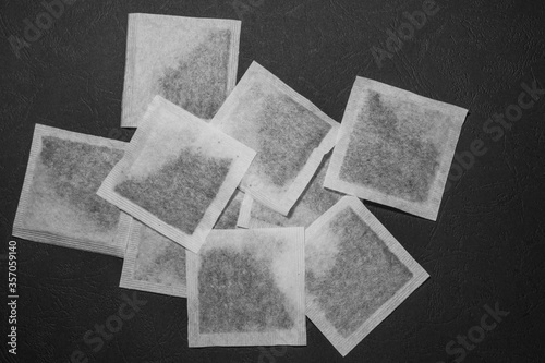 A bunch of square tea bags, lying chaotic on a black background