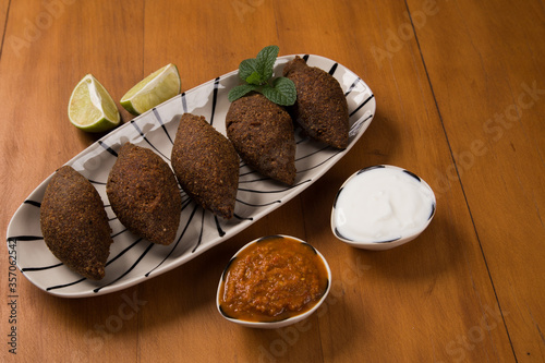 fried kibbeh served with yogurt sauce, and pepper sauce, on a plate photo