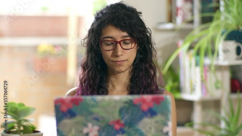 Freelance woman with glasses working at home with plants at background