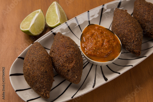 fried kibbeh served with pepper sauce, on a white plate. photo