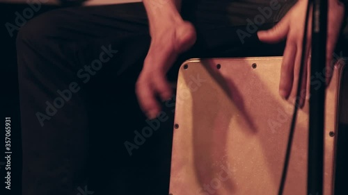 Close-up of a musician in a band performing music with flamenco cajon