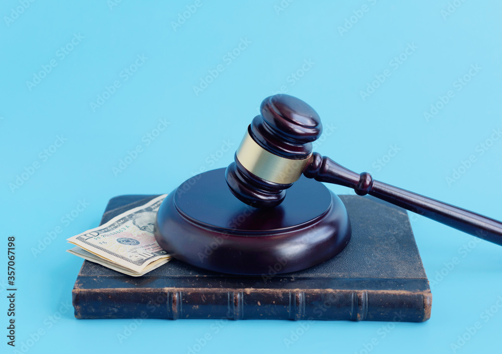 brown gavel and dollars on a blue background 