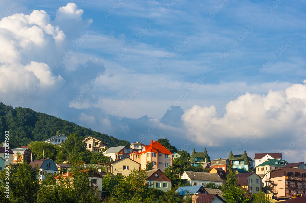 Resort village in mountain valley against the blue sky with clouds, summer landscape