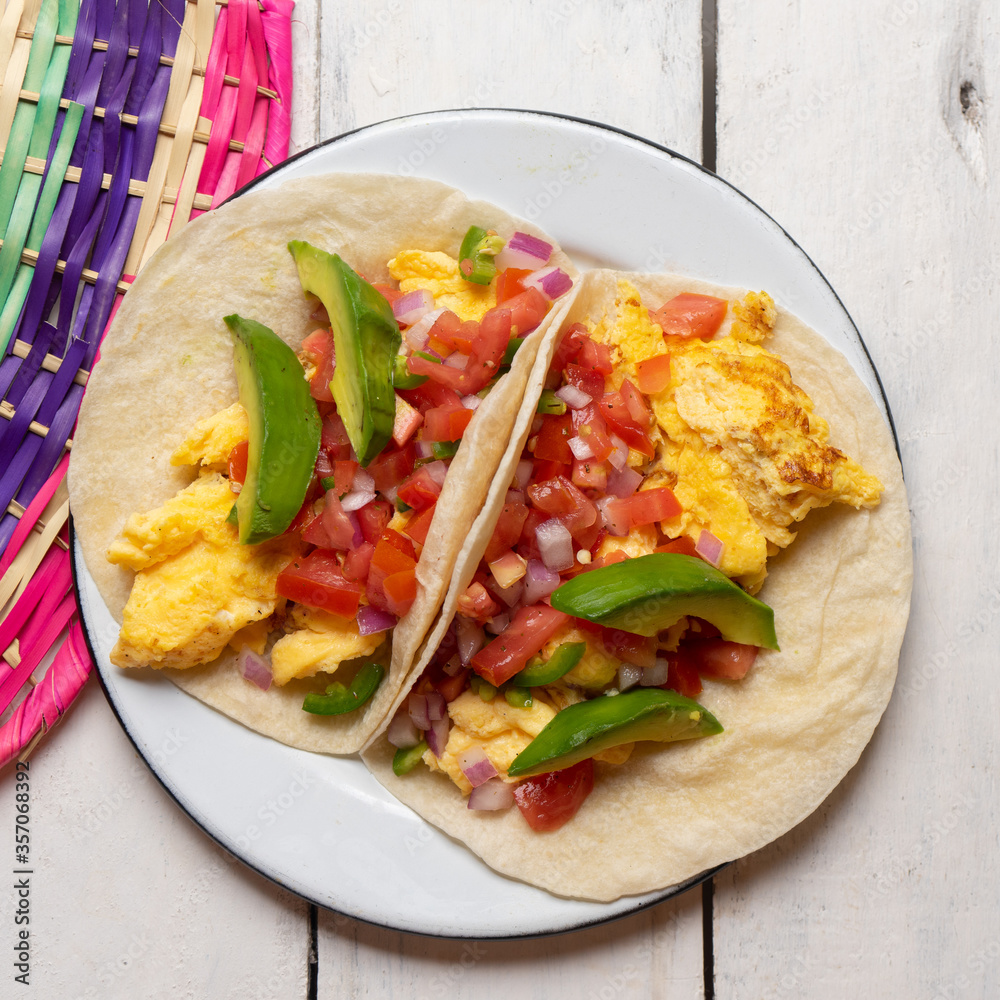 Breakfast egg tacos with flour tortilla and fresh sauce on white background