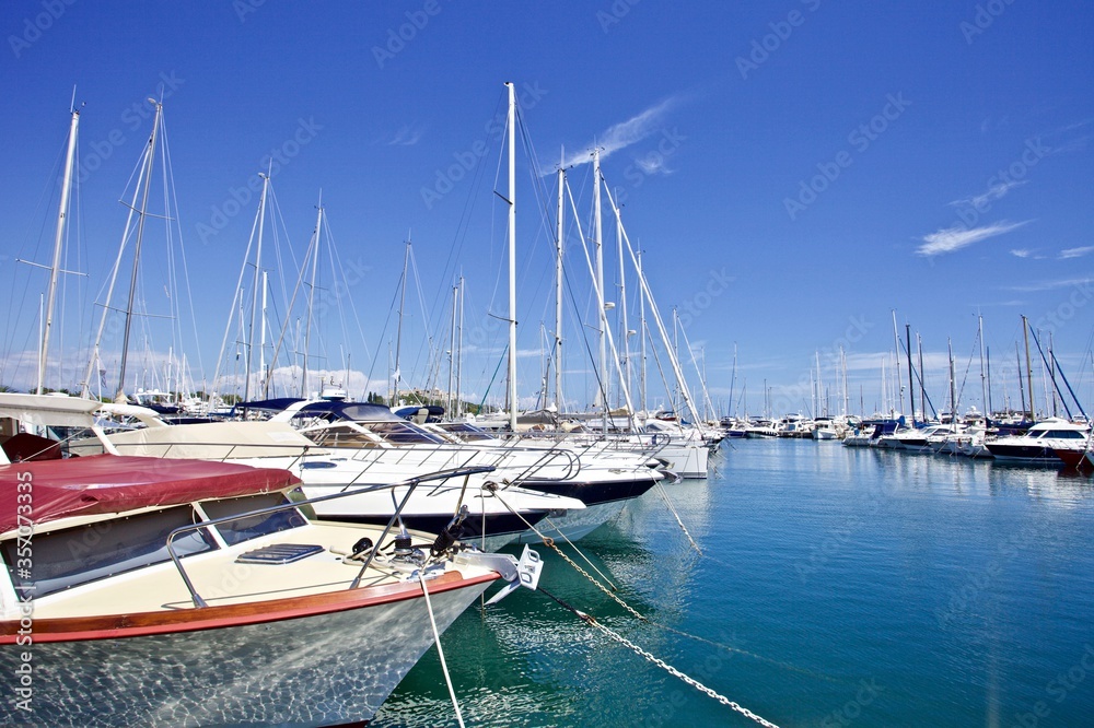 Yachts and speed boats at harbor. Yachts moored in the port. Ocean Coast pier. High class lifestyle. Yachting. Expensive toys. Sea ​​transport. Nautical. Yachting sport. Expensive yachts at the pier.