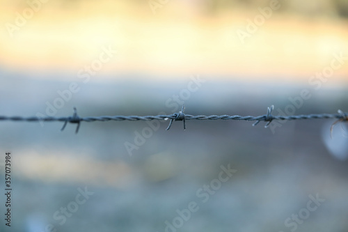 Close up image of barbed wire fence on frosty winter morning
