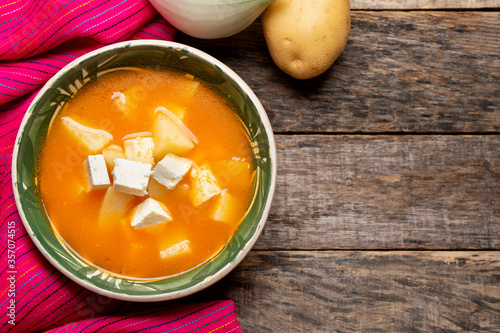 Mexican potato soup with panela cheese on wooden background photo