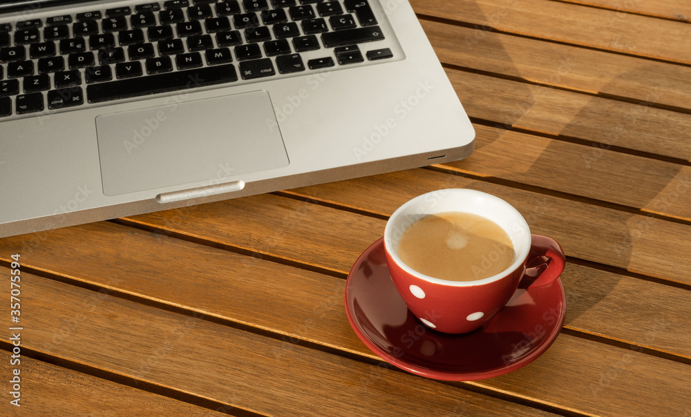 Laptop computer next to cup with coffee, on wooden table in the terrace, working in the confinement. Laptop computer next to cup with coffee, on wooden table in the terrace, working in the confinement.