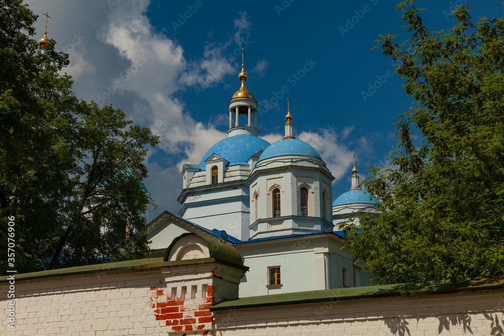 Orthodox church with blue domes and golden crosses. The church is surrounded by a stone fence.