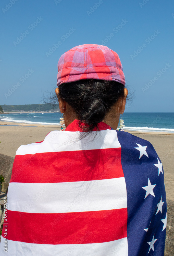 American Flag & Japanese Flag on an Asian lady while she is at the beach looking out to the Pacific ocean, lose to the Olympic surfing Venue in Chiba American Flag & Japanese Flag on an Asian lady while she is at the beach looking out to the Pacific ocean, lose to the Olympic surfing Venue in Chiba