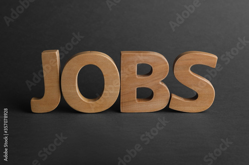 Word JOBS made with wooden letters on dark background. Career concept