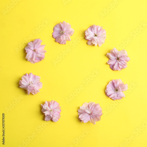 Frame made with beautiful sakura blossom on yellow background, space for text. Japanese cherry