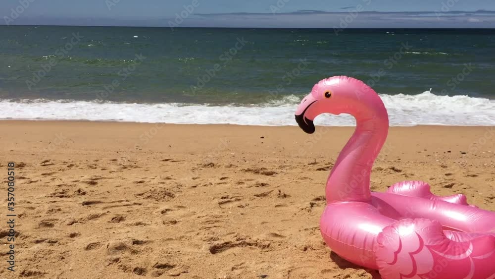 Inflatable Flamingo float on yellow sand beach natural outdoors background. High Res Full HD video.. Having fun vacations
