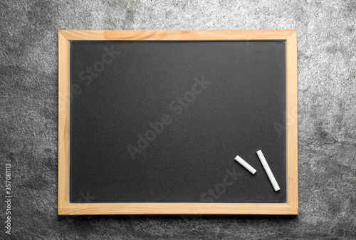 Empty blackboard with chalk on grey stone background, top view. Space for text