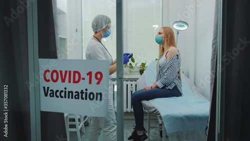 Young woman getting coronavirus vaccine in hospital. Covid-19 vaccination concept.