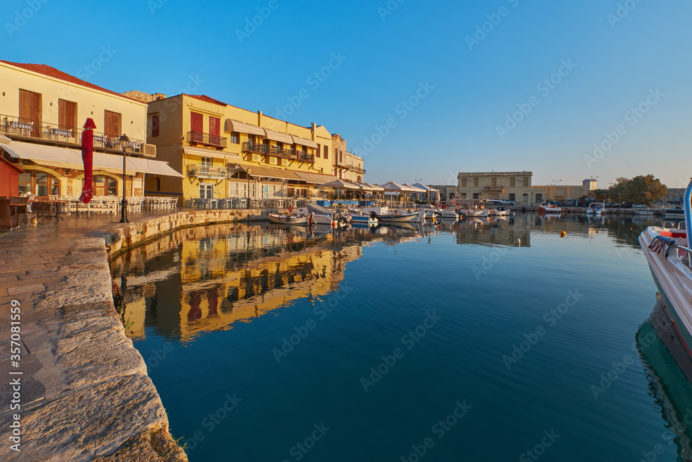 the quay of the historic port of Rethimno in the morning sun, boats in the port and empty restaurants