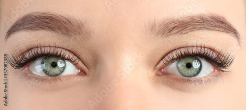 Young woman with beautiful eyelashes after extension procedure, closeup. Banner design