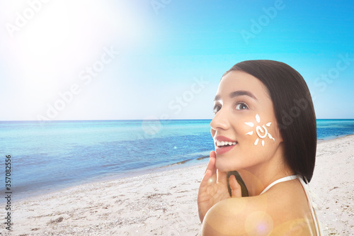 Tableau sur toile Young woman with sun protection cream on her face at beach, space for text