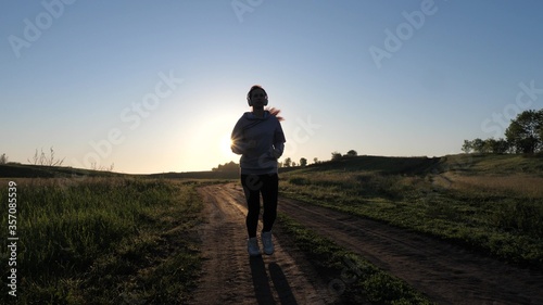 sports for burning calories and losing weight. young woman is training in summer in park at dawn in headphones with music. Free beautiful girl is engaged in fitness. Jogger girl breathes fresh air © zoteva87