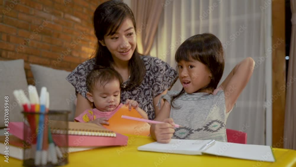 study disturbance. child studying at home in the evening with mother and baby sibling study disturbance. child studying at home in the evening with mother and baby sibling
