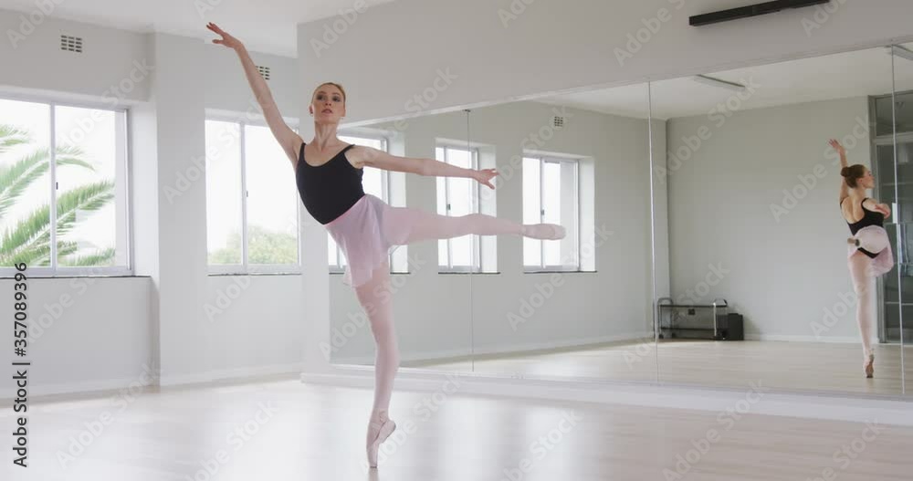 Caucasian female ballet dancer practicing ballet during a dance class in a bright studio Caucasian female ballet dancer practicing ballet during a dance class in a bright studio