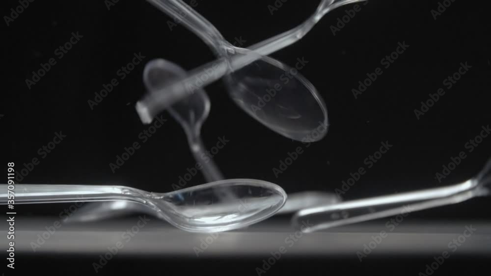 Transperent spoons falls on black background slow motion video. Transperent spoons falls on black background slow motion video.