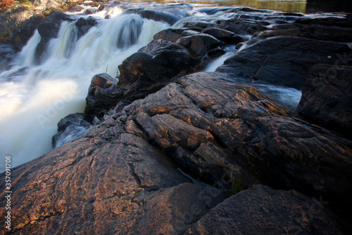 Bracebridge, Ontario / Canada - 10/11/2009: Smooth milky white waterfall on dark-colored rocks - side view- Long exposure.