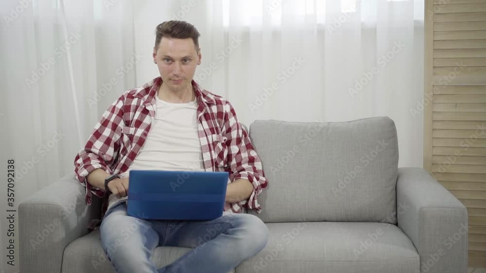 Young Caucasian man pressing key on laptop keyboard and money start falling on him. Slowmo of successful brunette guy earning income online. Concept of wealth, freelance, success. Young Caucasian man pressing key on laptop keyboard and money start falling on him. Slowmo of successful brunette guy earning income online. Concept of wealth, freelance, success.