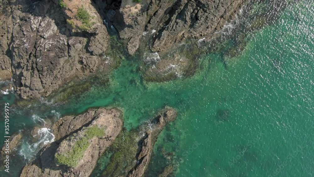 Aerial: Flying over rocky coastline and ocean waves looking down. Elliot bay, Northland, New Zealand Aerial: Flying over rocky coastline and ocean waves looking down. Elliot bay, Northland, New Zealand