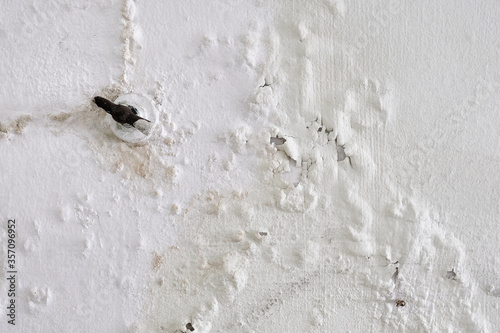 Water leakage from broken pipe behind wall causing water stains, peeling and bubbling wall paint.