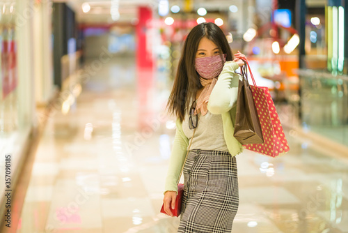 New normal habits - young attractive and happy Asian Korean woman at shopping mall happy and excited enjoying sale in beauty fashion store carrying shopping bags