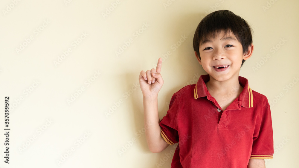 One lovely Asian boy is pointing the finger up like presenting something or getting some idea. The smart and creative kid concept. One lovely Asian boy is pointing the finger up like presenting something or getting some idea. The smart and creative kid concept.