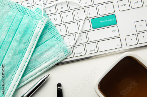 Concept work from home & new normal situation during Covid-19 Coronavirus pandemic virus outbreak update. keyboard with green button  coffee and medical face mask 