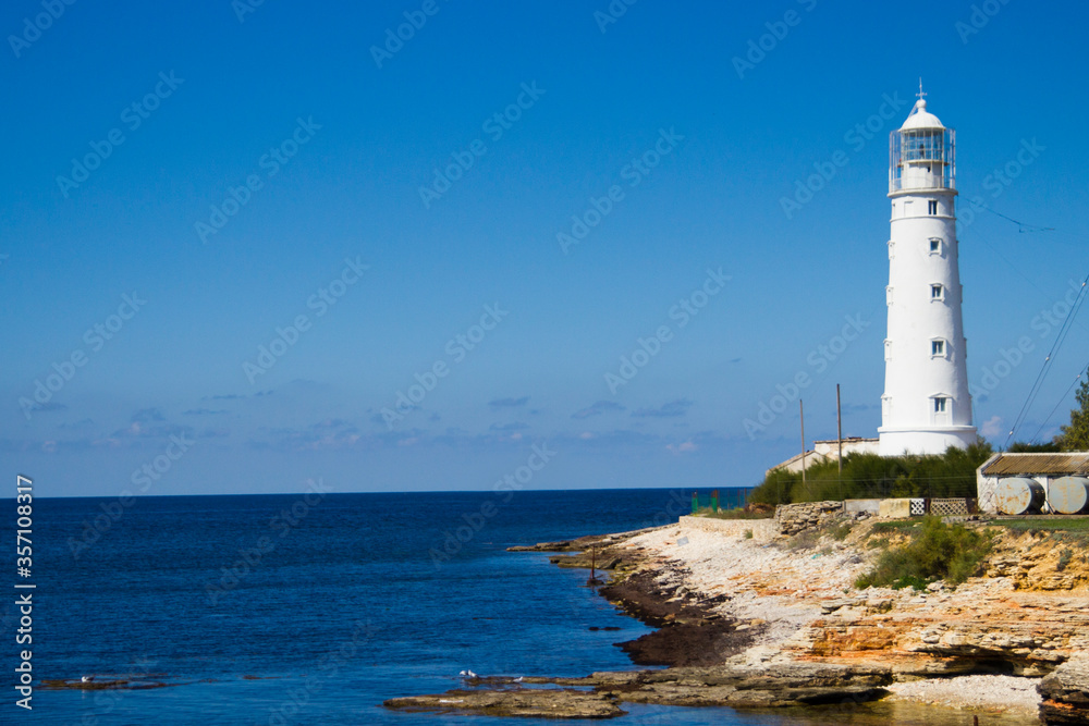 white lighthouse by the sea on a sunny summer day