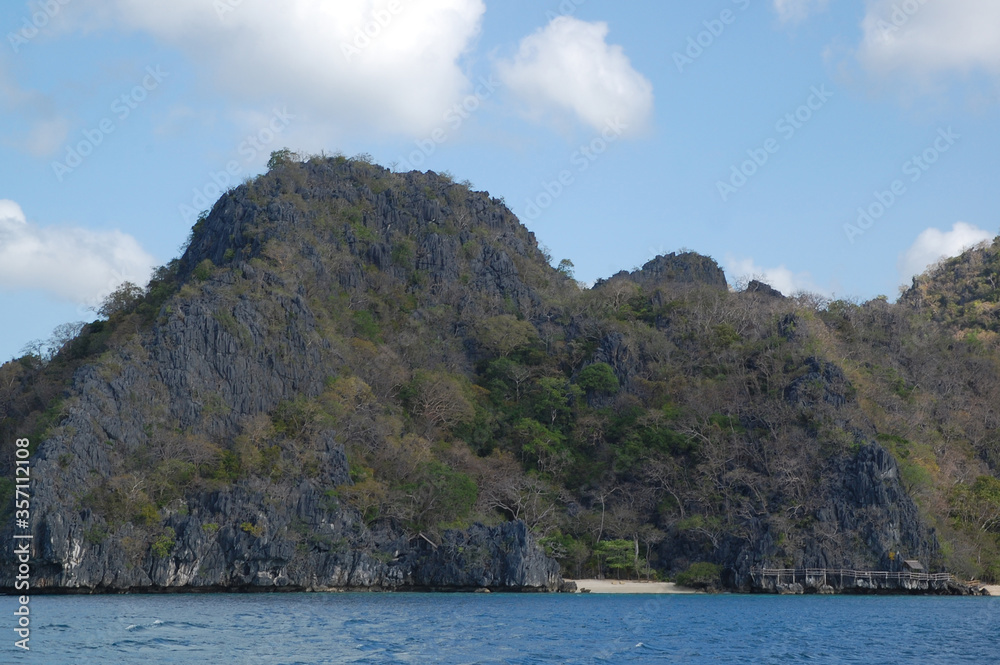 Limestone rock formation with sands, trees, and blue water sea