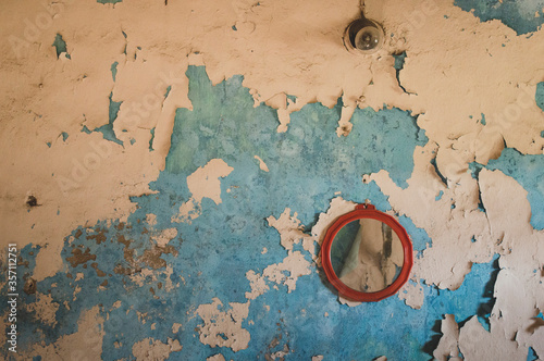 Obraz na płótnie A peeling wall, a round mirror, and a small lamp w salonie