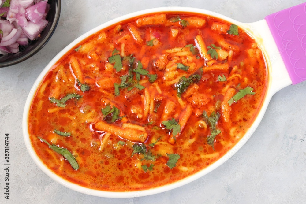 Traditional Sev bhaji or sev tamatar nu Shaak. its a sweet & spicy tomato curry topped with sev. Sev is a crisp fried gram flour vermicelli. Served with chopped onion and lemon. with Copy space. Traditional Sev bhaji or sev tamatar nu Shaak. its a sweet & spicy tomato curry topped with sev. Sev is a crisp fried gram flour vermicelli. Served with chopped onion and lemon. with Copy space.